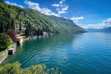 Como Gölü 'nün doğu kıyısının manzarası Villa Manastırı ve Fiumelatte kasabası bulutlu mavi gökyüzüne karşı