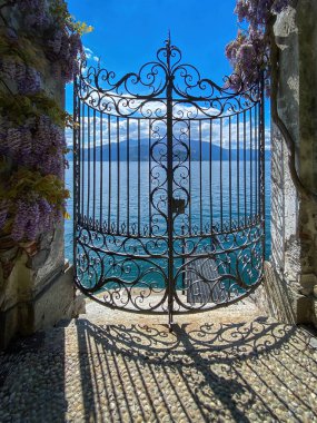 Como Gölü ve dağların kapalı demir kapısından görünüşü, İtalya bulutlu mavi gökyüzüne karşı