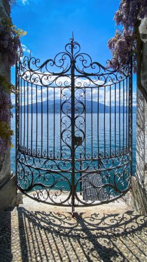 Como Gölü ve dağların kapalı demir kapısından görünüşü, İtalya bulutlu mavi gökyüzüne karşı