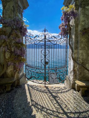 Como Gölü ve dağların kapalı demir kapısından görünüşü, İtalya bulutlu mavi gökyüzüne karşı