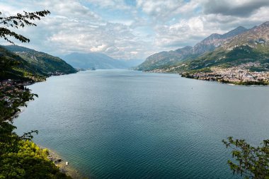 Mandello del Lario (sağda) ve Onno (solda) köyü ile kuzeye bakan Como Gölü ve güneydoğu dalının manzarası mavi gökyüzüne karşıdır.