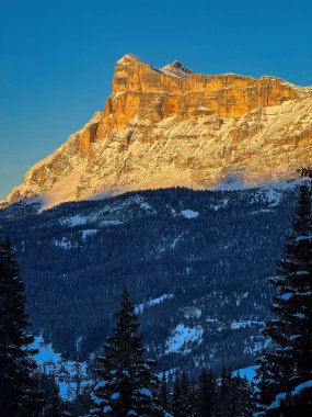 Scenic view of Heiligkreuzkofel mountain Sas dla Crusc in the Dolomites, South Tyrol, Italy in winter at sunset against blue sky clipart