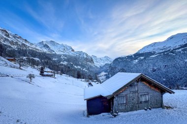 Lauterbrunnen Vadisi 'nin panoramik manzarası, İsviçre Wengen' den karla kaplı Breithorn (sağda) ve Jungfrau (solda) dağları ile mavi gökyüzü bulutlu