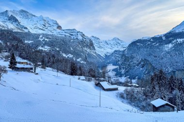 Lauterbrunnen Vadisi 'nin panoramik manzarası, İsviçre Wengen' den karla kaplı Breithorn (sağda) ve Jungfrau (solda) dağları ile mavi gökyüzü bulutlu