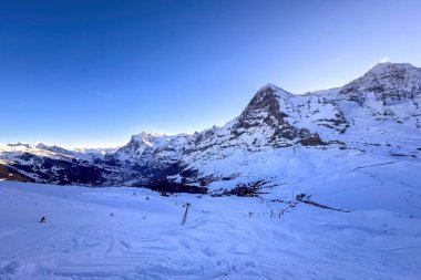 İsviçre 'de kar örtülü ünlü dağların panoramik manzarası Eiger ve Moench (soldan sağa) Grindelwald ve Wetterhorn (solda) ile birlikte sabah erken saatlerde mavi gökyüzüne karşı