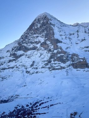 İsviçre 'de kar kaplı Eiger dağının manzarası sabahın erken saatlerinde mavi gökyüzüne karşı