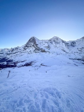 Sabahın erken saatlerinde İsviçre 'deki karla kaplı Eiger ve Moench dağlarının mavi gökyüzüne karşı manzarası