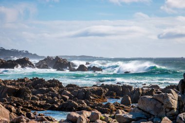 Pasifik Okyanusu kıyısındaki kayalık manzaralı 17 mil boyunca güneye bakan Del Monte Ormanı, Kaliforniya, ABD mavi gökyüzüne karşı bulutlu