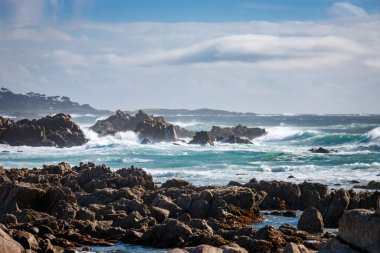 Pasifik Okyanusu kıyısındaki kayalık manzaralı 17 mil boyunca güneye bakan Del Monte Ormanı, Kaliforniya, ABD mavi gökyüzüne karşı bulutlu