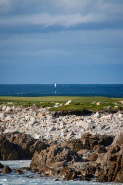 Monterey Peninsula Country Club (MPCC Dunes), Del Monte Forest, Kaliforniya, ABD 'de bulutlu gökyüzüne karşı kayalık Pasifik Okyanusu kıyısı manzarası