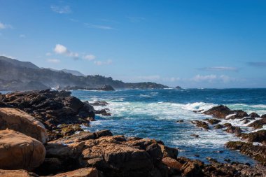 Point Lobos State Doğal Rezervi 'ndeki kayalık Pasifik Okyanusu sahili manzarası, Kaliforniya, ABD' de bulutlu mavi gökyüzüne karşı