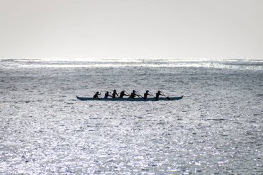 Avara Demiri kanosu, ABD 'nin Hawaii eyaletindeki Oahu adasının kıyısında tek bir teknede ışığa karşı kürek çekiyor.