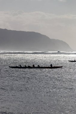 Oahu, Hawaii, ABD 'deki Waialua Körfezi' nde arka ışığa karşı Avara Kanosu kürek çekiyor.