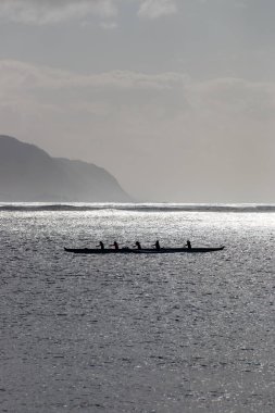 Oahu, Hawaii, ABD 'deki Waialua Körfezi' nde arka ışığa karşı Avara Kanosu kürek çekiyor.