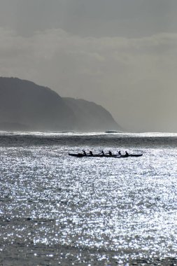 Oahu, Hawaii, ABD 'deki Waialua Körfezi' nde arka ışığa karşı Avara Kanosu kürek çekiyor.