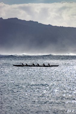 Oahu, Hawaii, ABD 'deki Waialua Körfezi' nde arka ışığa karşı Avara Kanosu kürek çekiyor.