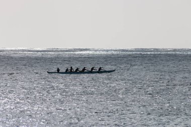Avara Demiri kanosu, ABD 'nin Hawaii eyaletindeki Oahu adasının kıyısında tek bir teknede ışığa karşı kürek çekiyor.