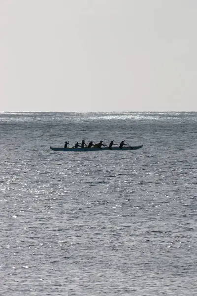 Avara Demiri kanosu, ABD 'nin Hawaii eyaletindeki Oahu adasının kıyısında tek bir teknede ışığa karşı kürek çekiyor.