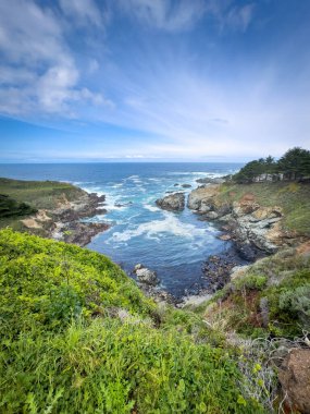Kaliforniya 'daki kayalık Pasifik Okyanusu kıyılarının manzarası, Kasler Point yakınlarında bulutlu mavi gökyüzüne karşı ABD