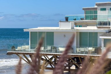 Malibu, California, ABD - 15 Nisan 2024: Deniz ve mavi gökyüzüne karşı Corral Sahili 'nin su kenarındaki sazlıklar üzerindeki sahil evi