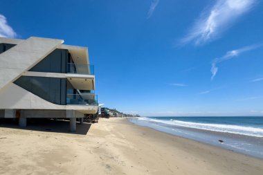 Malibu, California, ABD - 15 Nisan 2024: Mavi gökyüzüne karşı Carbon-La Costa Plajı 'ndaki su kenarındaki sazlıklar üzerindeki sahil evi