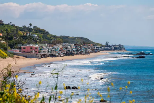 Corral Beach 'in manzarası ve deniz kenarındaki cambaz evleri, Malibu, California, ABD' de Nisan 2024 'te bulutlu mavi gökyüzüne karşı