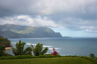 Hawaii 'nin Kauai adasının kuzey kıyısının manzarası ve Napali' nin ünlü kıyıları bulutlu gökyüzüne karşı.