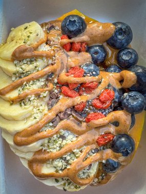Papaya Bowl kahvaltısı glütensiz granola, muz, yabanmersini, hindistan cevizi gevreği, goji üzümü, kenevir tohumu, chia tohumu, kakao ucu, bal ve fıstık ezmesi ile servis edilir.
