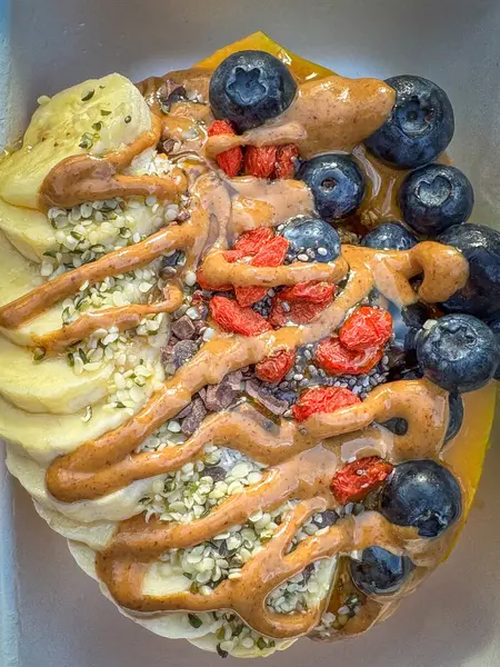 Papaya Bowl kahvaltısı glütensiz granola, muz, yabanmersini, hindistan cevizi gevreği, goji üzümü, kenevir tohumu, chia tohumu, kakao ucu, bal ve fıstık ezmesi ile servis edilir.