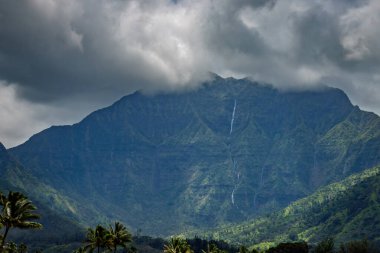 Halelea Ormanı 'nın manzarası, bulutlu gökyüzüne karşı Kauai, Hawaii' de şelalesi olan yeşil dağlar.