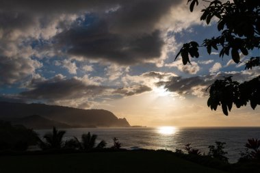 Hawaii 'nin Kauai adasının kuzey sahilinin arka plan manzarası. Gün batımında ünlü Napali sahili ile mavi gökyüzü bulutları karşı.