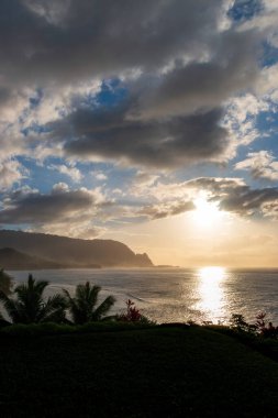 Hawaii 'nin Kauai adasının kuzey sahilinin arka plan manzarası. Gün batımında ünlü Napali sahili ile mavi gökyüzü bulutları karşı.