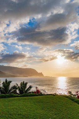 Hawaii 'nin Kauai adasının kuzey kıyısının manzarası. Gün batımında ünlü Napali kıyıları ile bulutlu mavi gökyüzüne karşı.