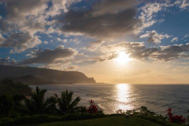 Hawaii 'nin Kauai adasının kuzey sahilinin arka plan manzarası. Gün batımında ünlü Napali sahili ile mavi gökyüzü bulutları karşı.