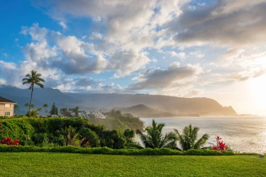 Hawaii 'nin Kauai adasının kuzey kıyısının manzarası. Gün batımında ünlü Napali kıyıları ile bulutlu mavi gökyüzüne karşı.