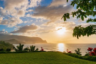 Hawaii 'nin Kauai adasının kuzey kıyısının manzarası. Gün batımında ünlü Napali kıyıları ile bulutlu mavi gökyüzüne karşı.
