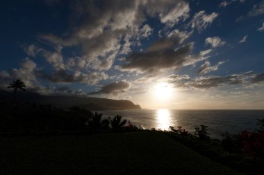 Hawaii 'nin Kauai adasının kuzey sahilinin arka plan manzarası. Gün batımında ünlü Napali sahili ile mavi gökyüzü bulutları karşı.