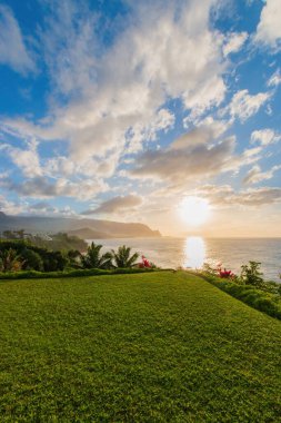 Hawaii 'nin Kauai adasının kuzey kıyısının manzarası. Gün batımında ünlü Napali kıyıları ile bulutlu mavi gökyüzüne karşı.