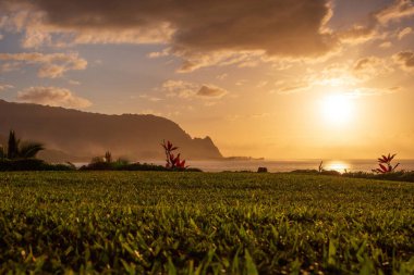 Hawaii 'nin kuzeyindeki Kauai adasının manzaralı ve alçak açılı manzarası. Gün batımında ünlü Napali kıyılarıyla mavi gökyüzüne karşı bulutlar.