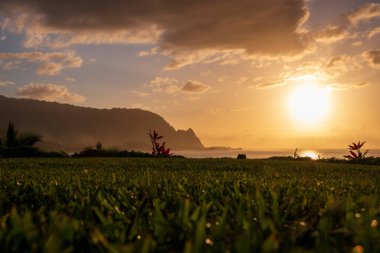 Hawaii 'nin kuzeyindeki Kauai adasının manzaralı ve alçak açılı manzarası. Gün batımında ünlü Napali kıyılarıyla mavi gökyüzüne karşı bulutlar.
