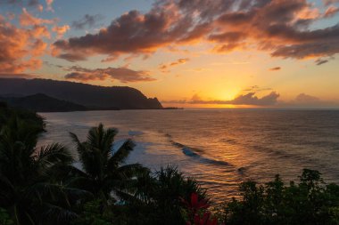Hawaii 'nin Kauai adasının kuzey kıyısının manzarası. Gün batımında ünlü Napali kıyıları ile bulutlu mavi gökyüzüne karşı.