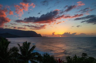 Hawaii 'nin Kauai adasının kuzey kıyısının manzarası. Gün batımında ünlü Napali kıyıları ile bulutlu mavi gökyüzüne karşı.