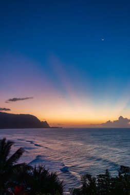 Hawaii 'nin Kauai adasının kuzey kıyısının manzarası. Gün batımından sonra meşhur Napali kıyısı bulutlu mavi gökyüzüne karşı.