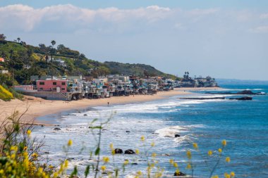 Corral Beach 'in manzarası ve deniz kenarındaki cambaz evleri, Malibu, California, ABD' de Nisan 2024 'te bulutlu mavi gökyüzüne karşı