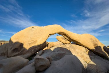 Günbatımında mavi gökyüzüne karşı sıcak ışıklarda Joshua Tree Ulusal Parkı, Kaliforniya 'daki ünlü Arch Rock oluşumunun manzarası