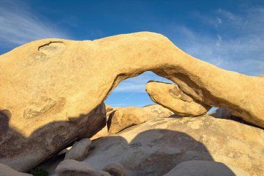 Günbatımında mavi gökyüzüne karşı sıcak ışıklarda Joshua Tree Ulusal Parkı, Kaliforniya 'daki ünlü Arch Rock oluşumunun manzarası