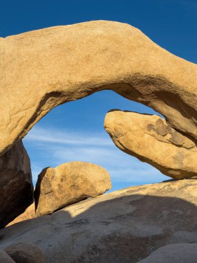 Günbatımında mavi gökyüzüne karşı sıcak ışıklarda Joshua Tree Ulusal Parkı, Kaliforniya 'daki ünlü Arch Rock oluşumunun manzarası