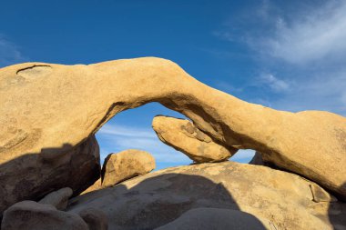 Günbatımında mavi gökyüzüne karşı sıcak ışıklarda Joshua Tree Ulusal Parkı, Kaliforniya 'daki ünlü Arch Rock oluşumunun manzarası