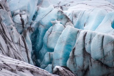 İzlanda 'daki Vatnajkull Ulusal Parkı' ndaki Svnafellskull buzulunda derin yarıkların ve çarpıcı mavi buz oluşumlarının yakın görüntüsü.