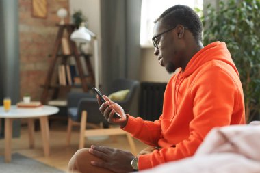 Yan görüntülerde Afro-Amerikalı genç adam oturma odasında oturmuş akıllı telefonundaki e-postaları kontrol ediyor, boşluğu kopyalıyor.